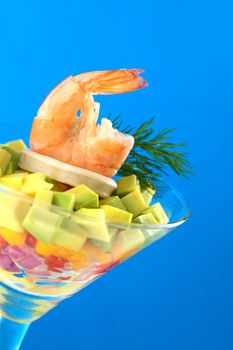 King prawn on a salad of onion, pepper, mango and avocado and a calamari ring, garnished with dill in a cocktail glass (Selective Focus, Focus on the king prawn)