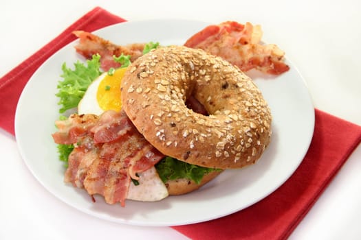 Bagel with salad, fried egg and crispy bacon