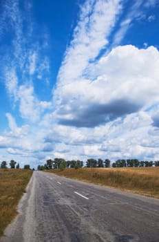 old asphalt road passes through farm fields