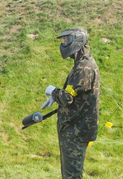 A teen in camouflage and mask ready for paintball.