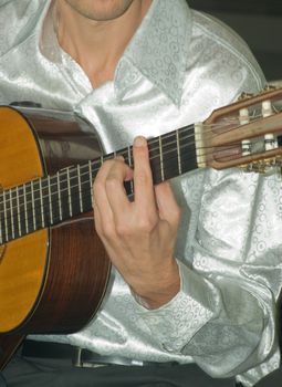 Closeup of man's hands playing classical acoustic guitar