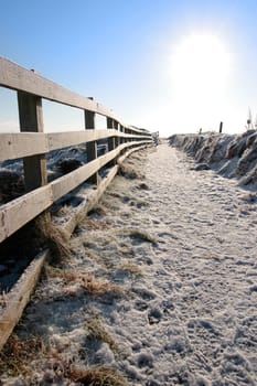 frosty blue winters view at ballybunion cliffside walk with bright sun and fence