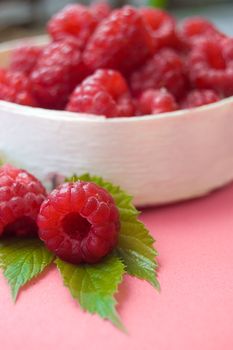 Raspberries in wooden basket with leaves