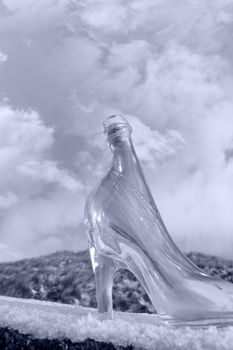 a glass slipper on a snow covered surface with a cloudy sky background in black and white