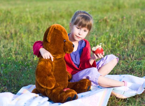 girl with teddy bear in a meadow. best friends.