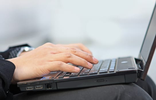 Hands typing on laptop computer keyboard close up