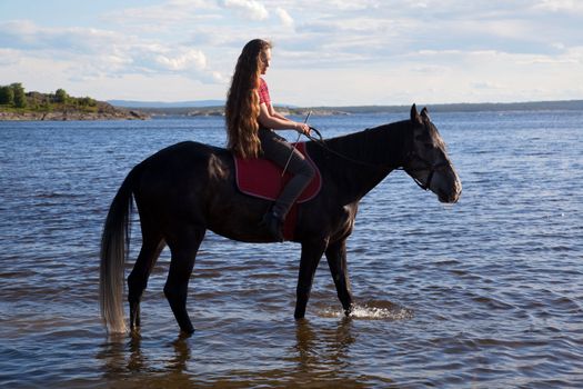 The girl has a horse to water in the evening at sunset