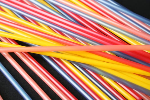 Straws on a black background in a variety of colours