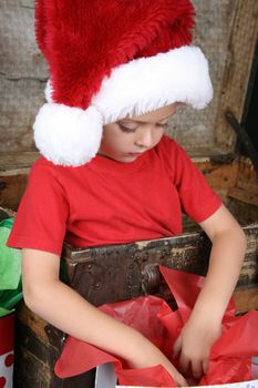 You boy wearing a christmas hat looking in his gift bag
