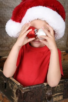Cute christmas boy playing peek-a-boo with decorations