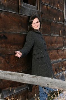 Beautiful brunette female leaning against a barn wall