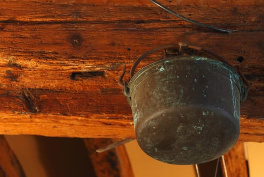 Old rusty copper pot hanging in a girder