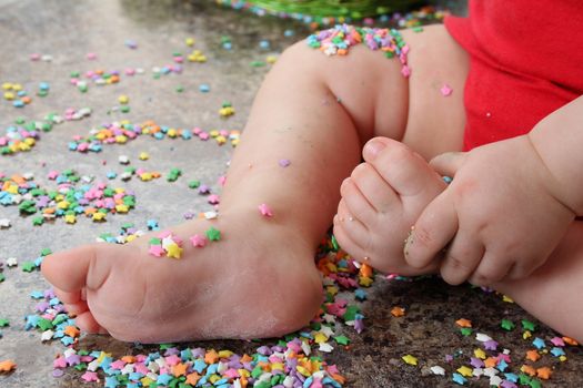 Baby feet and hand on kitchen countertop surrounded with cake decorations