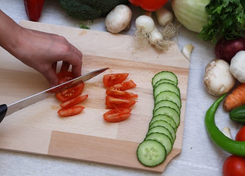 Detail of a knife and hand cutting a tomato.
