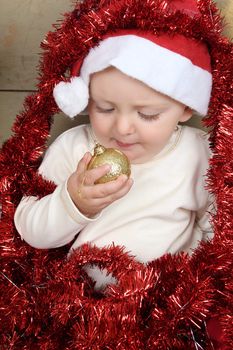 Cute baby boy wearing a christmas hat playing with decorations