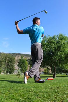 Young male golfer following a shot from the tee