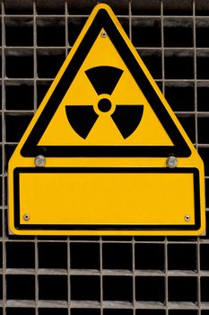 Nuclear radiation sign bolted to steel grid with blank copyspace for your message.