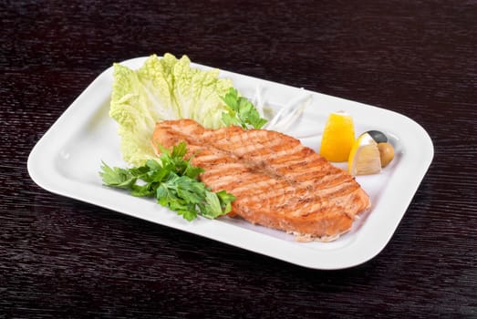 Grilled salmon steak with greens,onion, lemon, lime and olive