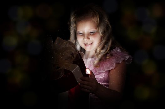 girl opens a box with a gift, beams therefrom shine and magic opens