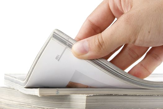 man hand browsing through stack of magazines