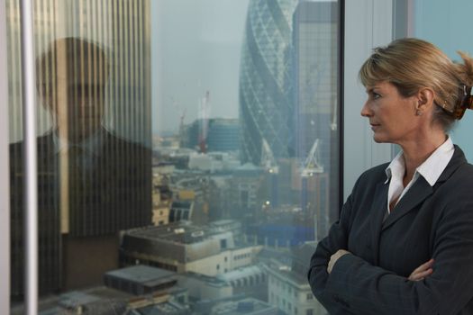 Business woman looking out of window with reflection of business man looking back
