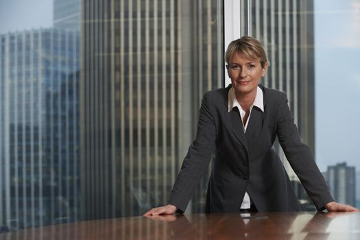 Business woman leaning on chair in boardroom looking at camera