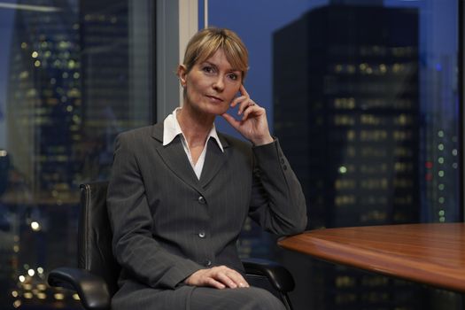 Business woman sitting at table in boardroom looking at camera