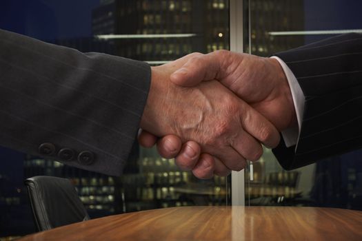 shaking hands over boardroom table with city lights in background
