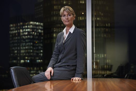 Business woman sitting at table in boardroom looking at camera