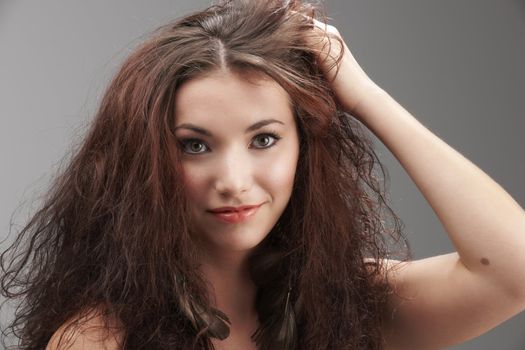 woman grabbing her tangled hair in frustration on grey background