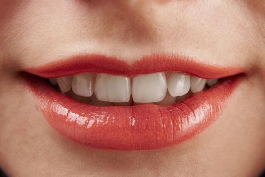 close-up of woman smiling with glosssy red lipstick