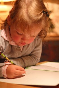 little girl writing with pencil on a sheet of paper