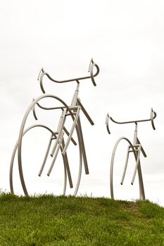Steel sculpture of bikes on grass.