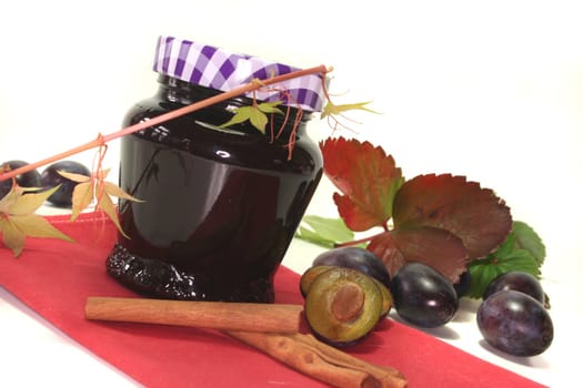 a glass of plum jam with fresh ingredients