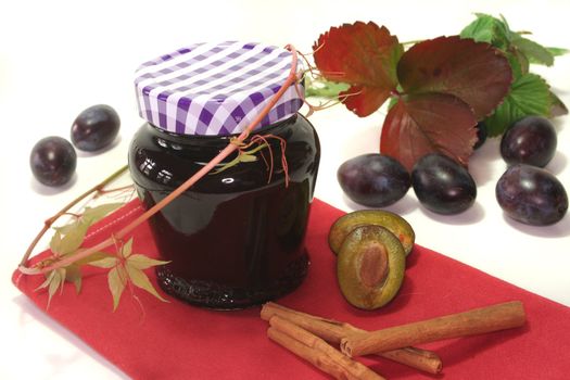 a glass of plum jam with fresh ingredients
