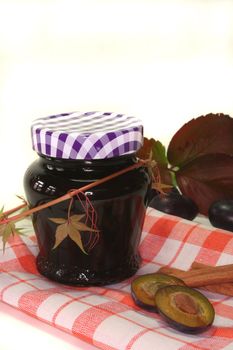 a glass of plum jam with fresh ingredients