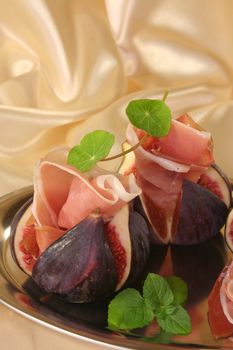 Figs with Serrano ham and nasturtium on a silver platter