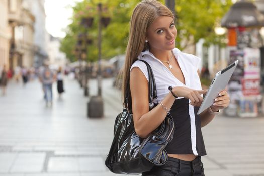 Young Beautiful Business Woman with tablet computer walking on urban street, downtown