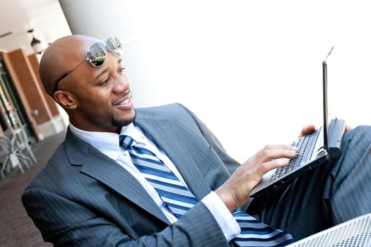 An African American business man in his early 30s using his laptop or netbook computer outdoors with copy space for your text.