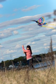 A young brunette woman flies a kite at the beach on a nice day.