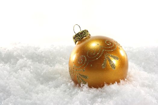 one golden Christmas ball lies in the snow