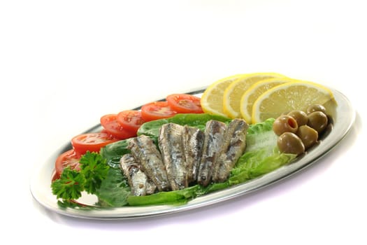 Anchovies served on lettuce with tomato, olives and lemon