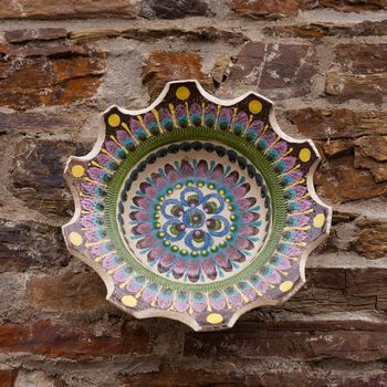 Decorative ceramic bowl on rough stone wall.