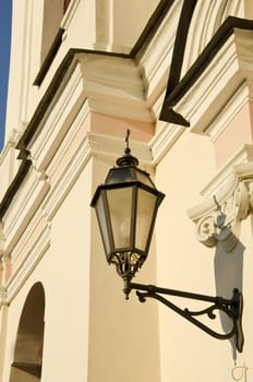 Metal illuminator on ancient white wall of building.