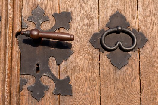 Iron door handle knob and keyhole on heavy wooden door.