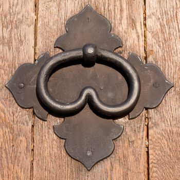 Iron door handle on heavy wooden door.