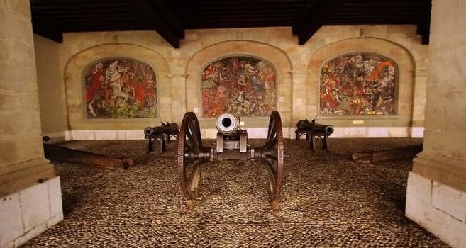 Various black cannons and paintings behind them in the old city of Geneva, Switzerland.