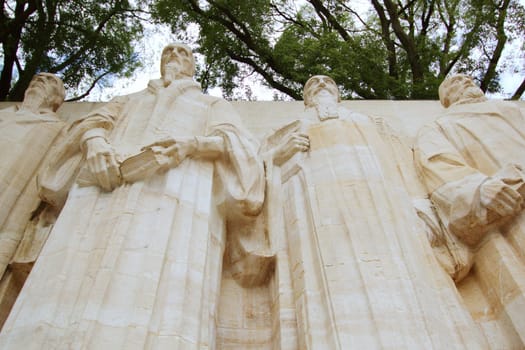 Sculptures of the four great figures of the geneva protestant movement : Guillaume Farel (1489 - 1565), Jean Calvin (1509-1564), Theodore de Beze (1513-1605) and John Knox (1513-1572) on the reformation wall in Bastions park, Geneva, Switzerland. The construction of this wall started in 1909. The motto of the Reformation and Geneva is written behind these statues : "Post Tenebras Lux.".