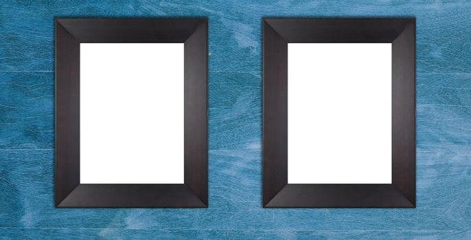 Two blank wooden black frames on blue painted wooden wall.