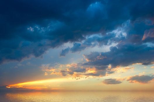 colorful sunset with clouds and sunbeams over rural skyline